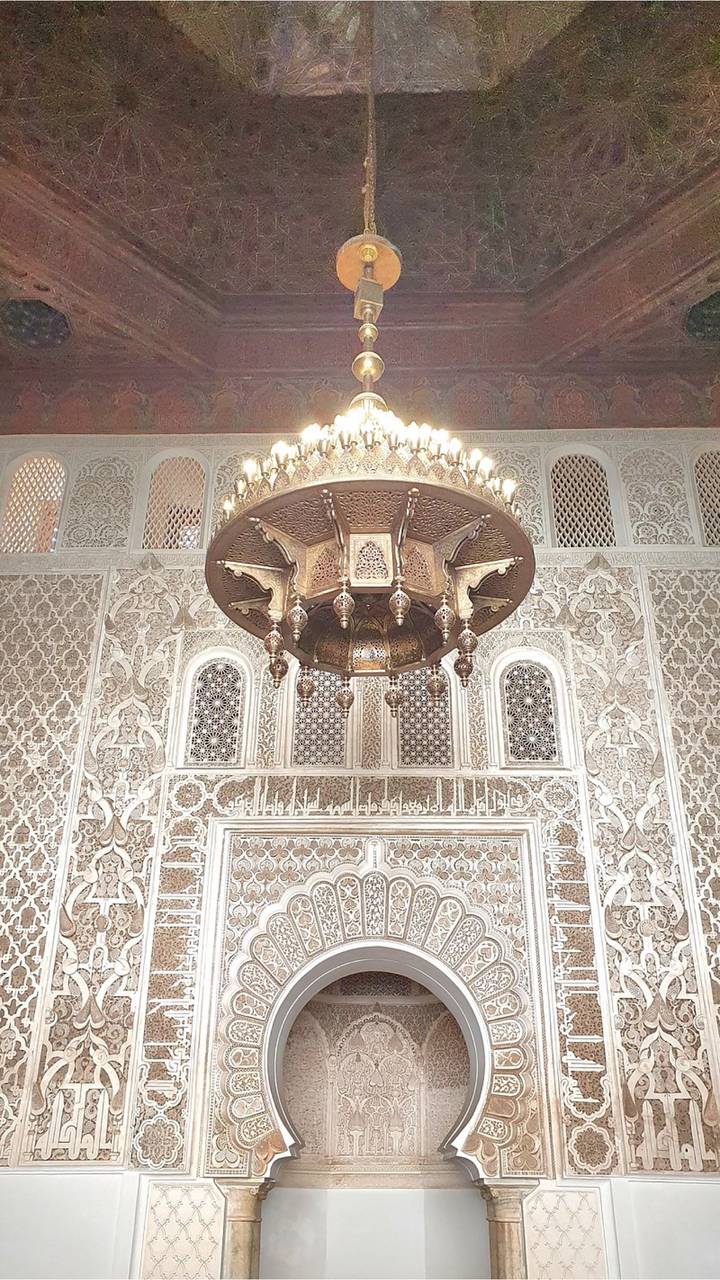 Intricate chandelier hanging in richly decorated interior of a Moroccan madrasa