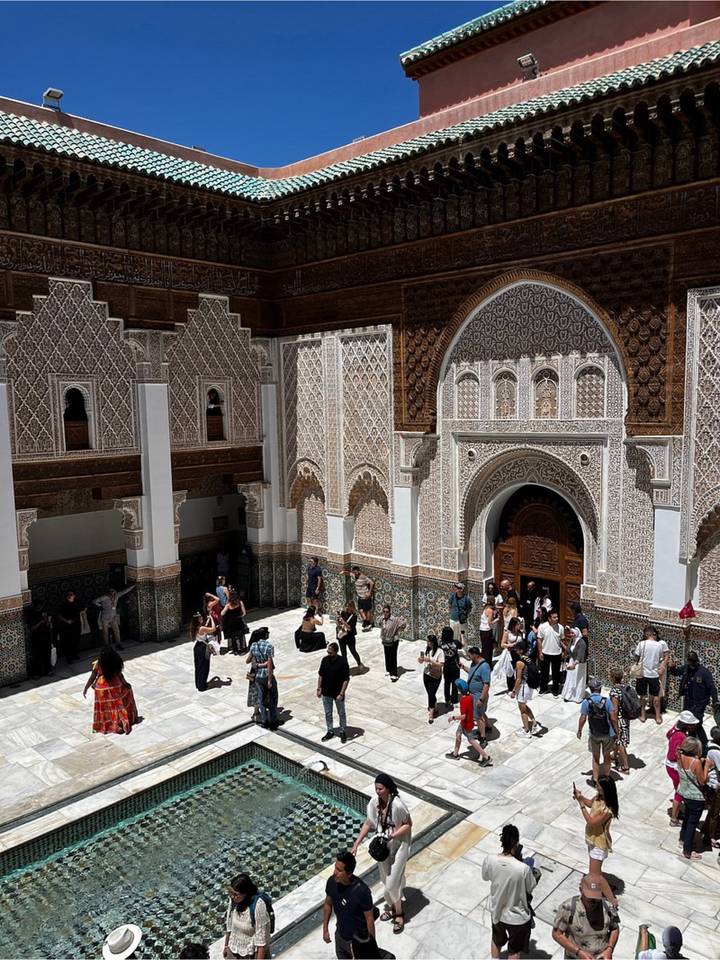 Large group of tourists gathered in tiled courtyard of Medersa Ben Youssef