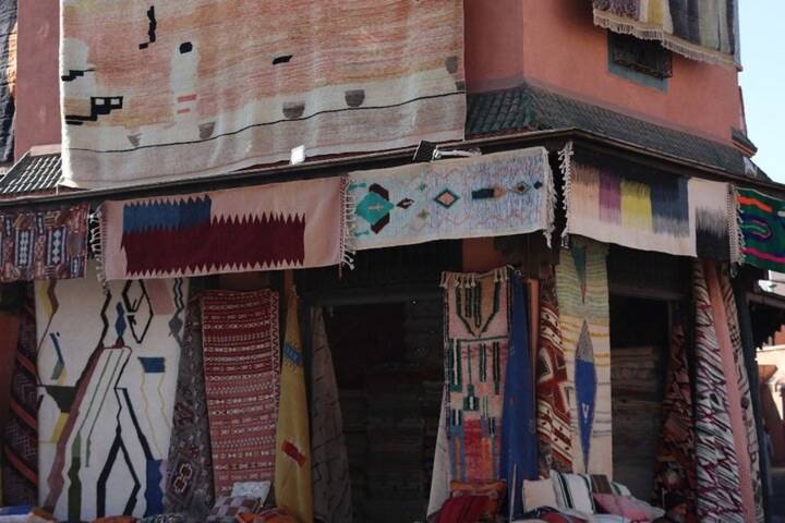 Corner rug shop with colorful carpets hanging on ochre building in the medina