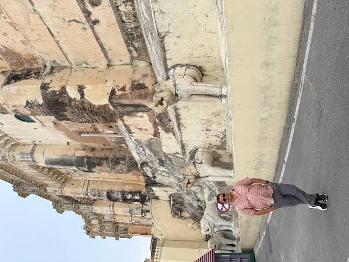 Man stands by weathered fort wall adorned with stone elephant sculptures at Amber Fort.