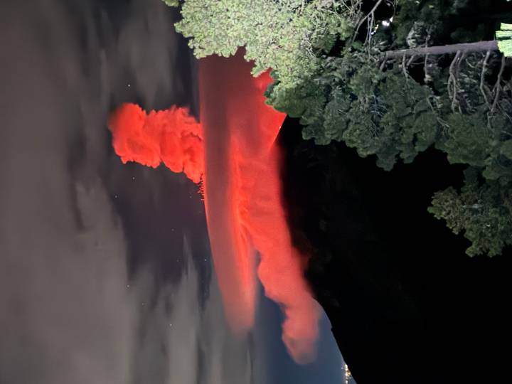 Nighttime eruption casts a red glow above Acatenango Volcano under a starry sky.