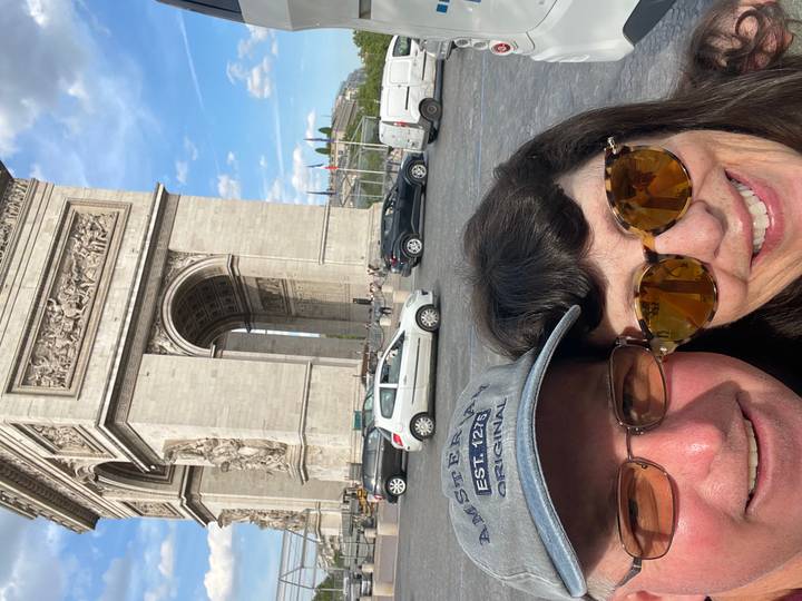 Selfie of couple in front of Paris’s Arc de Triomphe on a sunny afternoon.