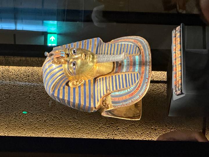 Golden funerary mask of Tutankhamun displayed in a museum showcase