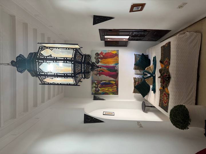 Elegant riad bedroom with lantern chandelier, colorful art and towel swans on the bed.