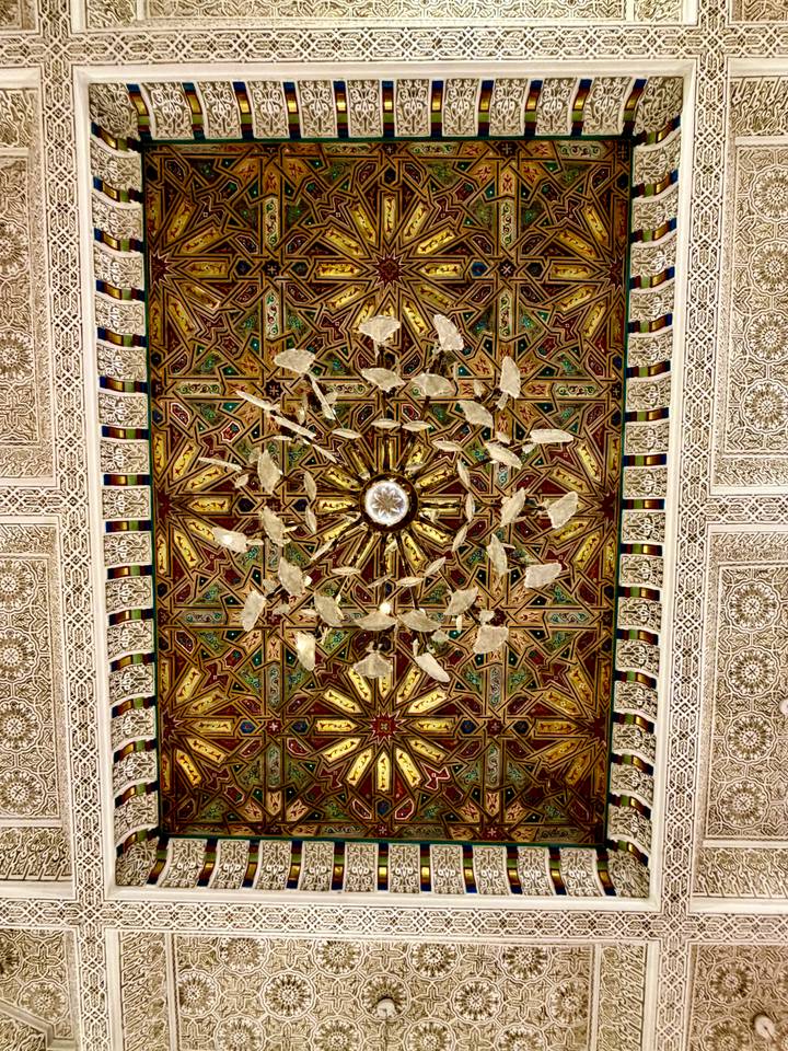 Close-up of an intricate gilded Moroccan ceiling with symmetrical geometric patterns.