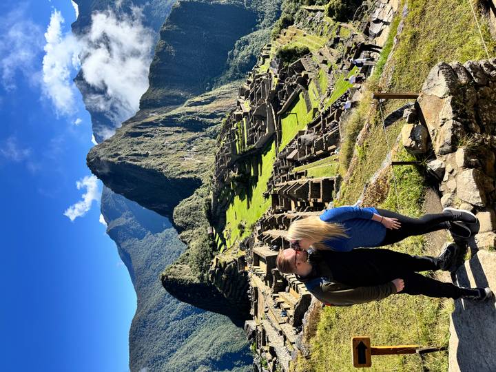 Couple sharing a kiss at the classic panoramic viewpoint over Machu Picchu ruins and Huayna Picchu peak