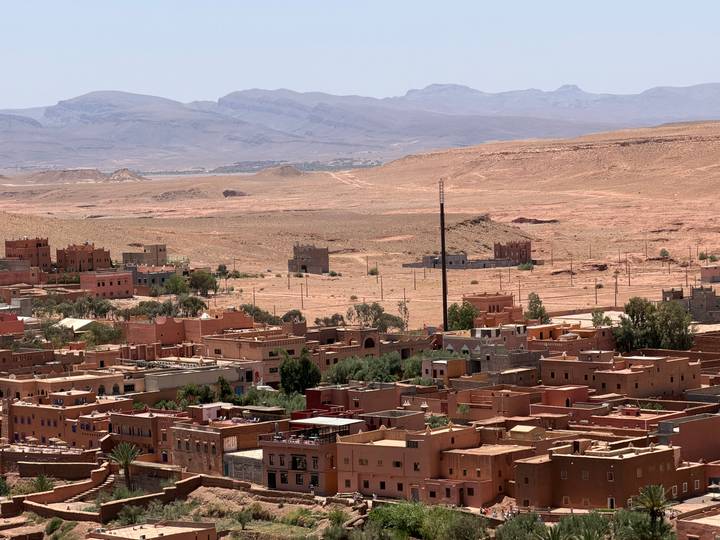 Desert town with flat-roofed adobe buildings set against arid plains and distant mountain range