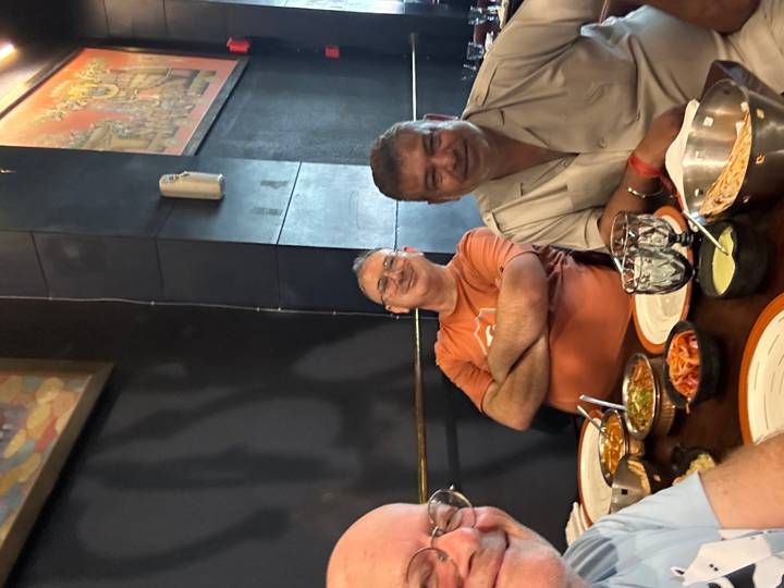 Two men enjoy a meal at an Indian restaurant table filled with curries, bread and condiments.