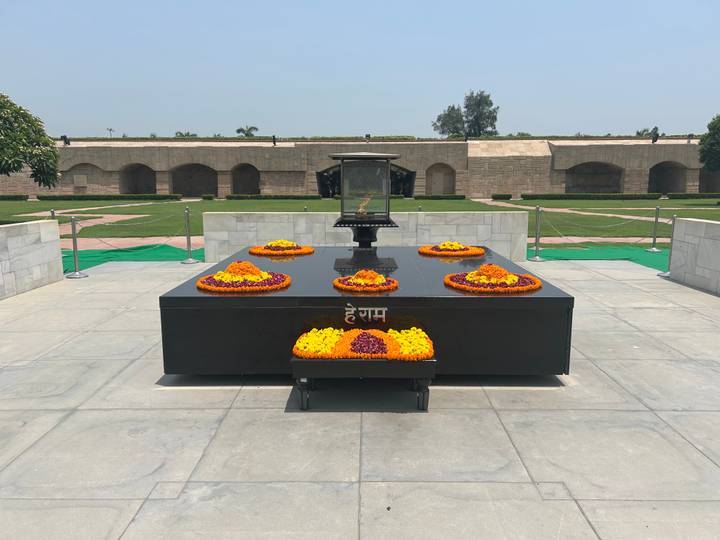 Black marble platform with an eternal flame and flower wreaths at Raj Ghat memorial.