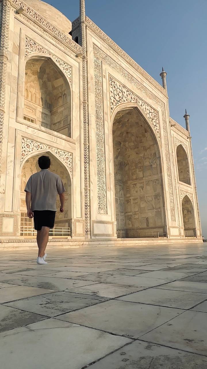 Traveller walks along marble terrace beside intricate arches of the Taj Mahal