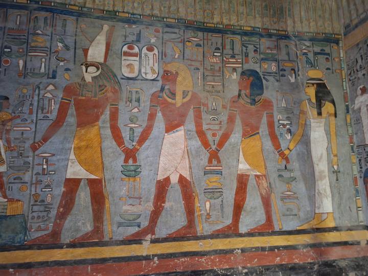 Colorful, detailed wall reliefs of ancient Egyptian deities inside a tomb.