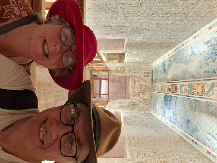 Close selfie of couple inside a color-rich, hieroglyph-covered tomb corridor.