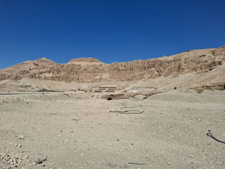 Wide desert vista with Hatshepsut Temple nestled against rugged cliffs.