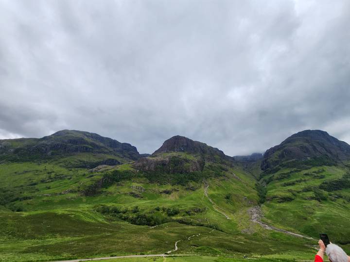 Green Scottish highland mountains beneath a dramatic gray sky in Glencoe.