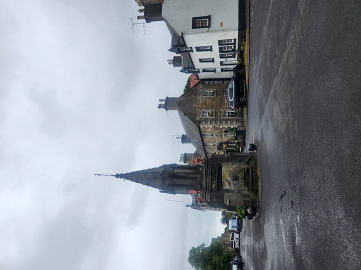 Quaint Scottish village square featuring historic stone buildings and a small monument.