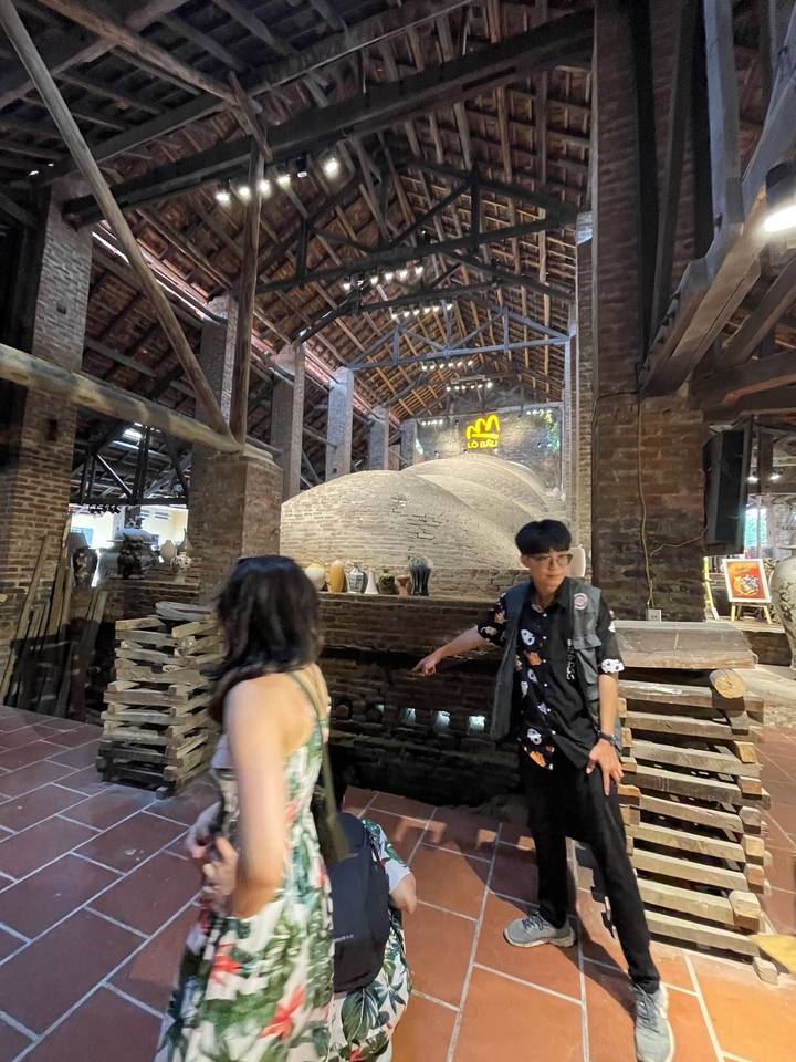 Guide showing visitors a large traditional brick kiln inside a rustic workshop