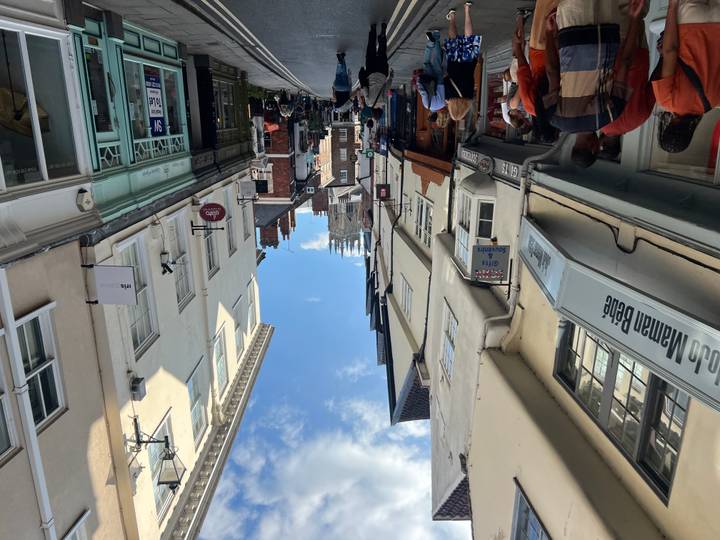 Narrow medieval street with shops leading to York Minster under a bright blue sky.