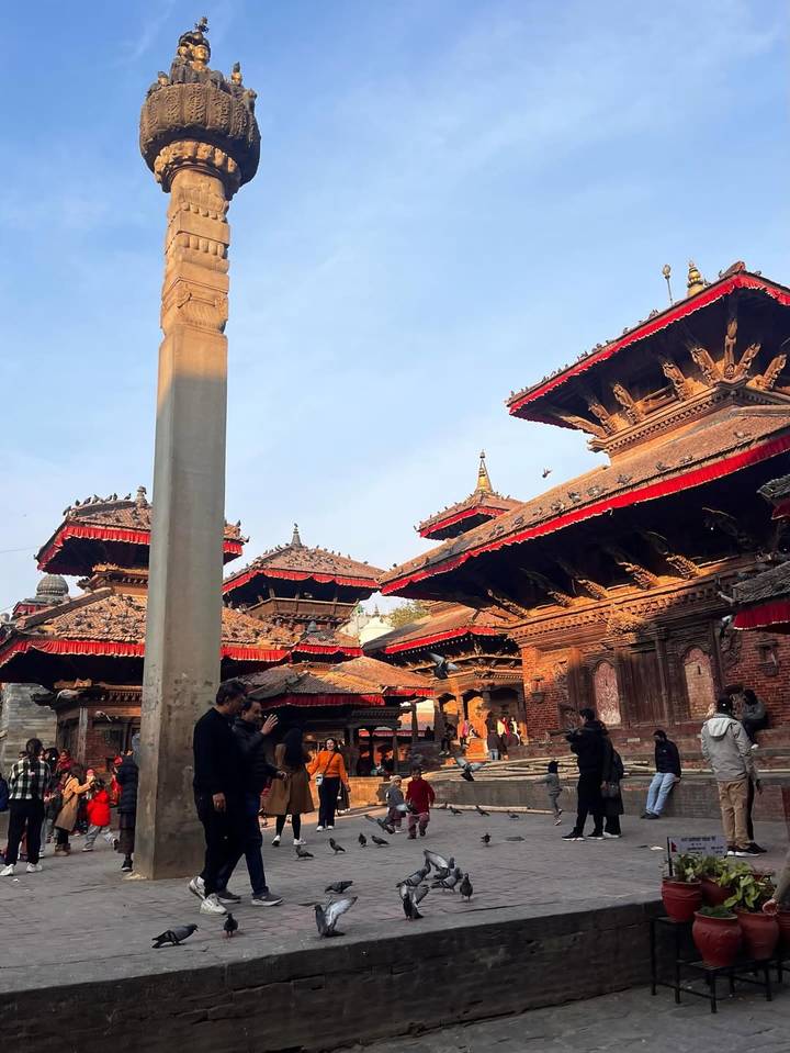 Historic pagoda-roofed temples with red canopies in Kathmandu Durbar Square illuminated by warm late-day light.