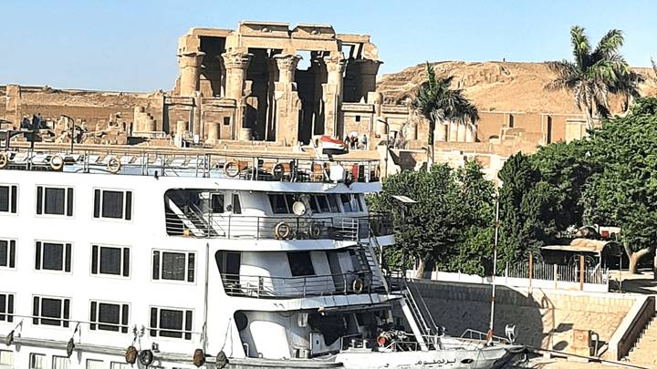 White Nile cruise boat docked with Kom Ombo Temple ruins visible on the opposite bank.