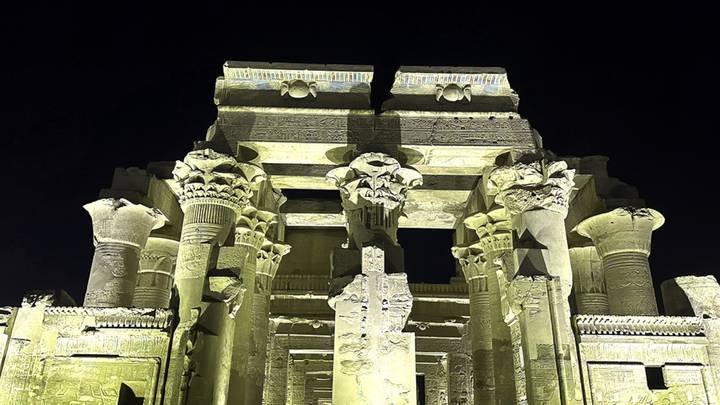 Nighttime lighting of Kom Ombo Temple columns casting dramatic shadows.