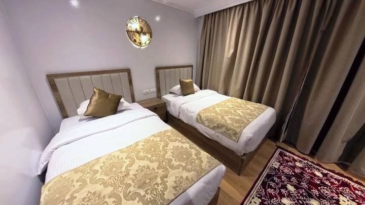 Compact twin cabin with gold patterned bedding and heavy curtains aboard Nile cruise boat.