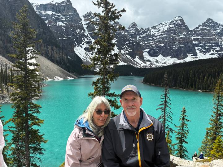 Smiling couple poses before Moraine Lake’s bright turquoise water and towering peaks.