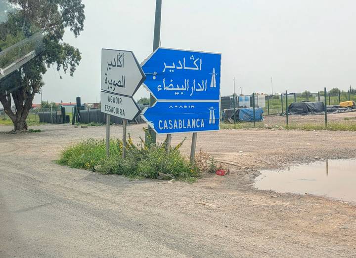 Junction signs indicating routes to Agadir, Casablanca and Essaouira beside a rural road