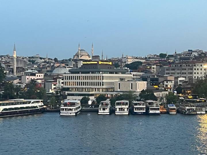 Evening waterfront view of Istanbul with ferries docked and illuminated mosques on the skyline.