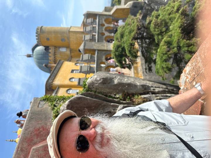 Portrait-style shot of traveler with partial view of Pena Palace domes and walls behind.