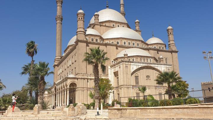 The grand Mosque of Muhammad Ali with its twin minarets rising over palm trees in Cairo.