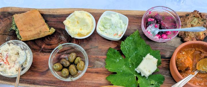 Rustic appetizer board with olives, cheeses, dips and bread on wooden platter