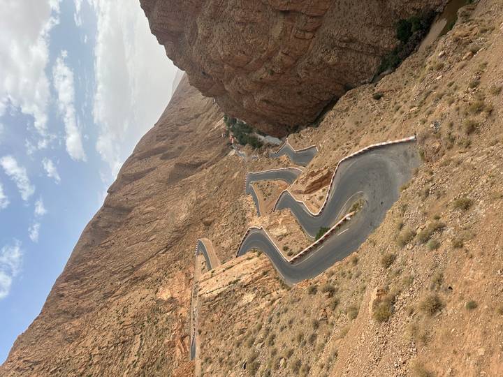 Famous winding road snakes through steep reddish mountains of Dades Gorge