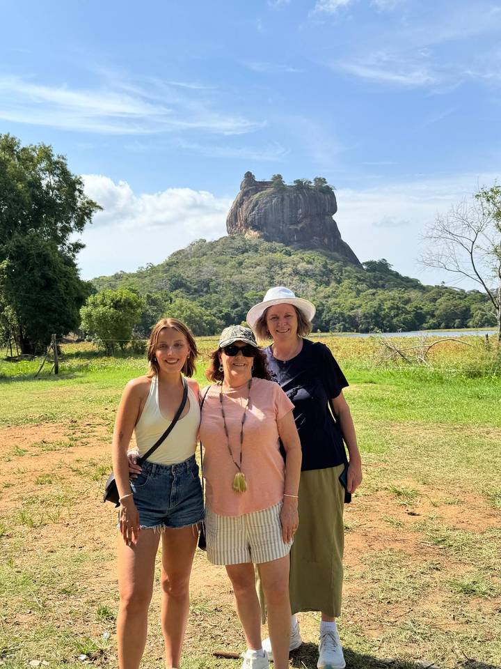 Three travelers posing with Sigiriya Rock Fortress towering in the background