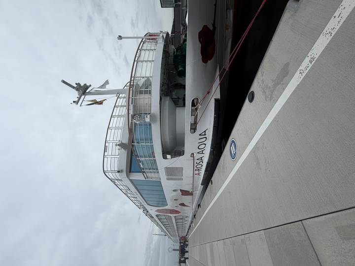 White A-Rosa Aqua river cruise ship docked at a concrete pier under grey skies