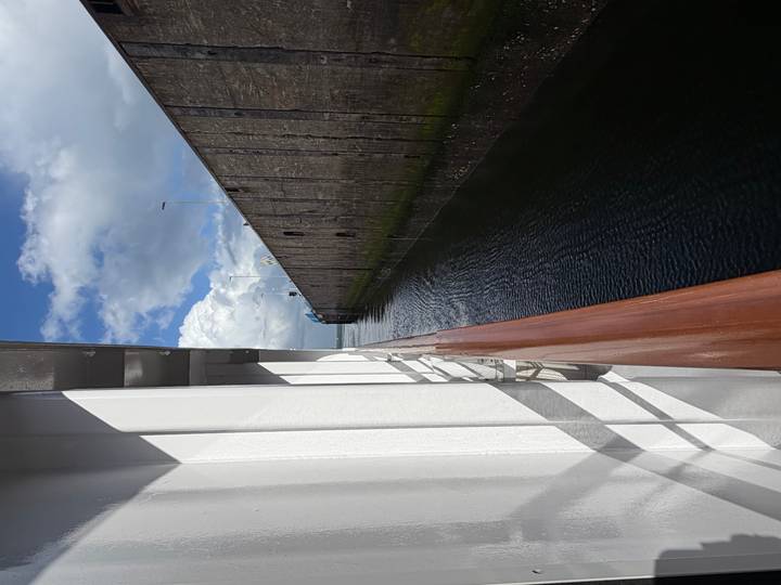 Side view from a river cruise ship entering a high-walled lock chamber under a mix of sun and clouds.