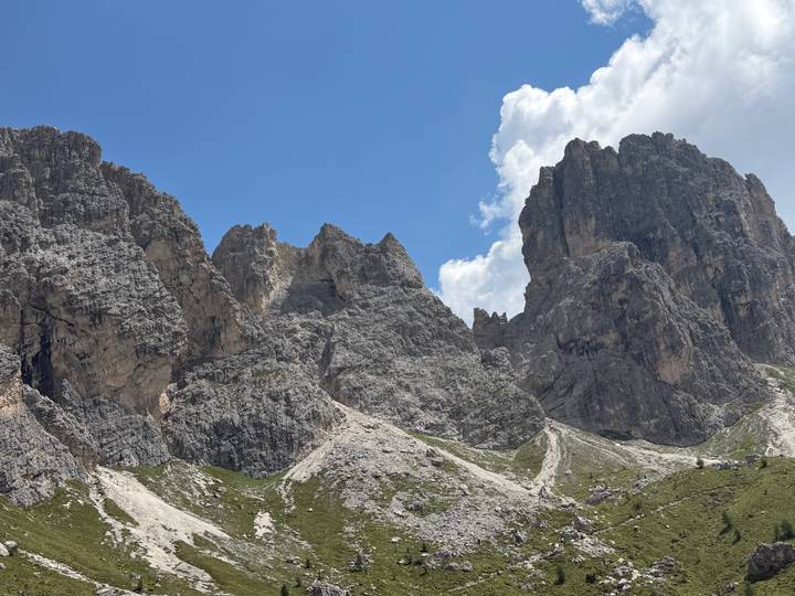 Rugged grey rock towers and scree slopes under a brilliant blue alpine sky.