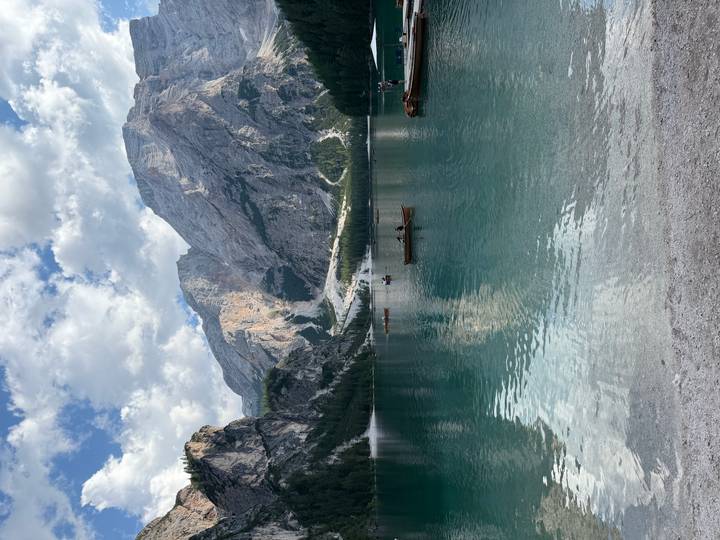 Crystal clear lake with rowboats and towering Dolomite cliffs reflected in the still water.