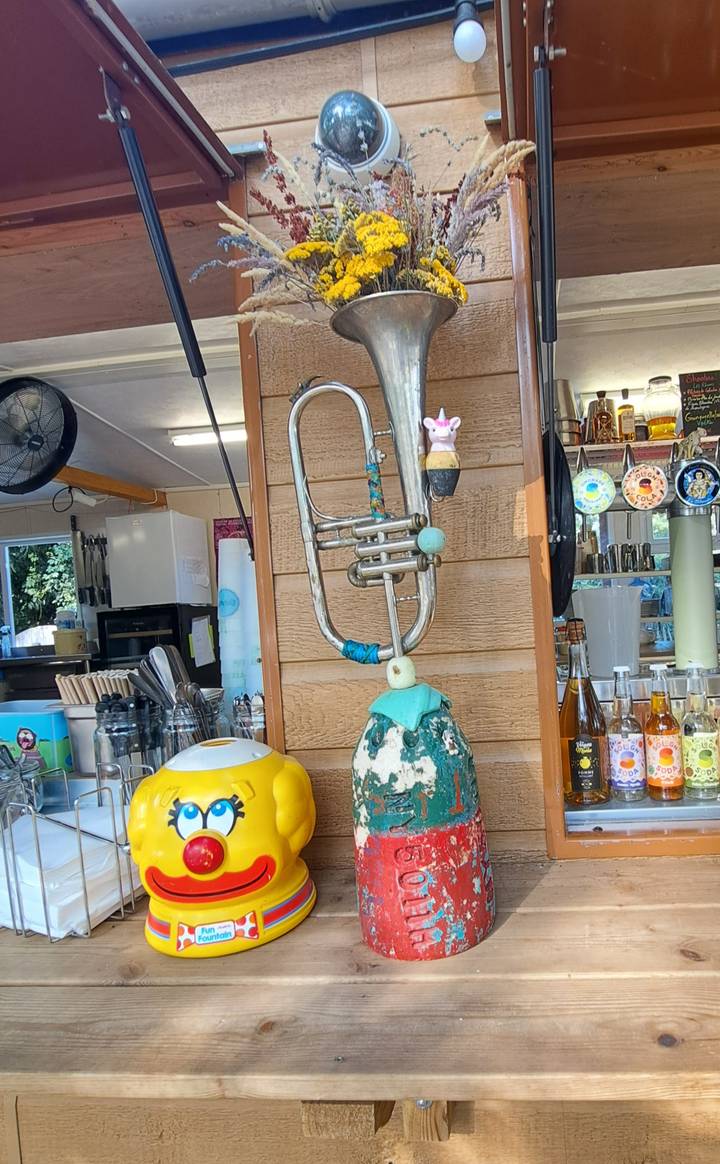 Interior bar counter featuring a whimsical sculpture made from a trumpet and a globe amid bottles and utensils