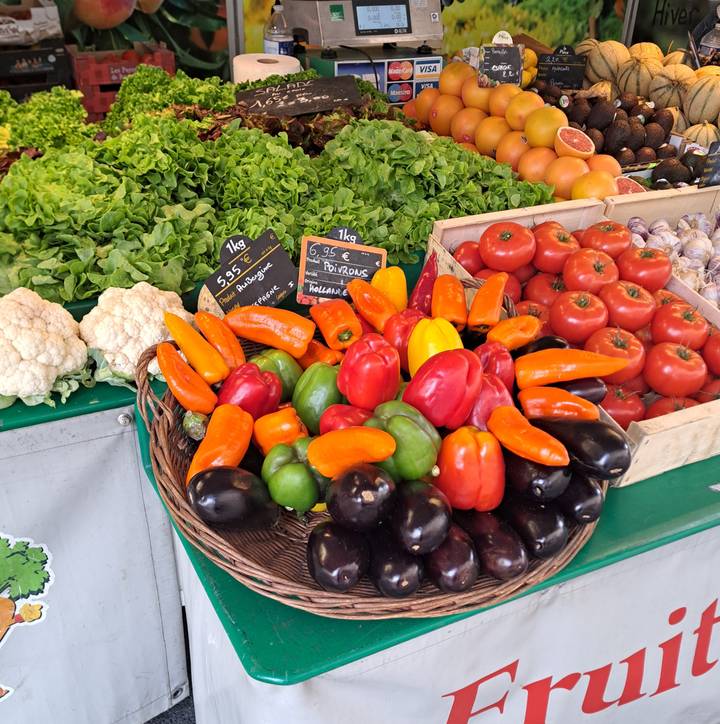 Vibrant display of assorted fresh vegetables and peppers at an outdoor market stall