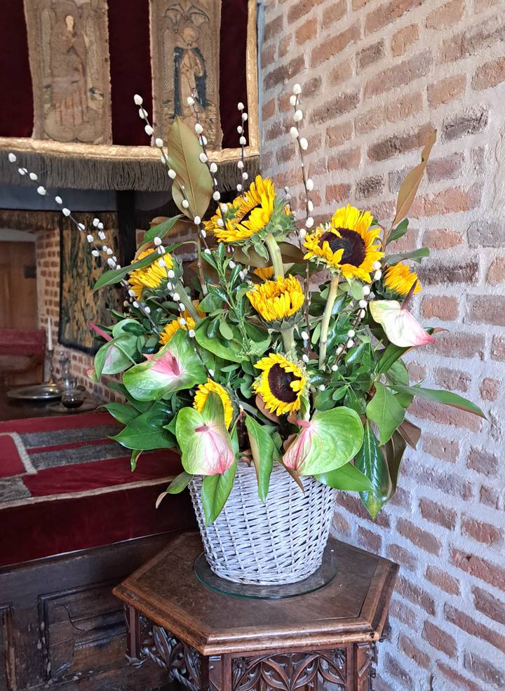 Arrangement of sunflowers and greenery in a rustic interior with brick walls