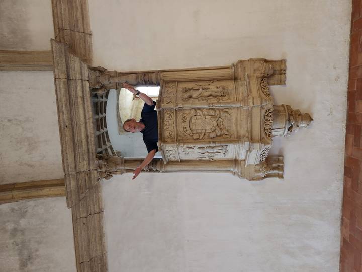 Man posing with arms raised in an ornate stone pulpit inside a historic church