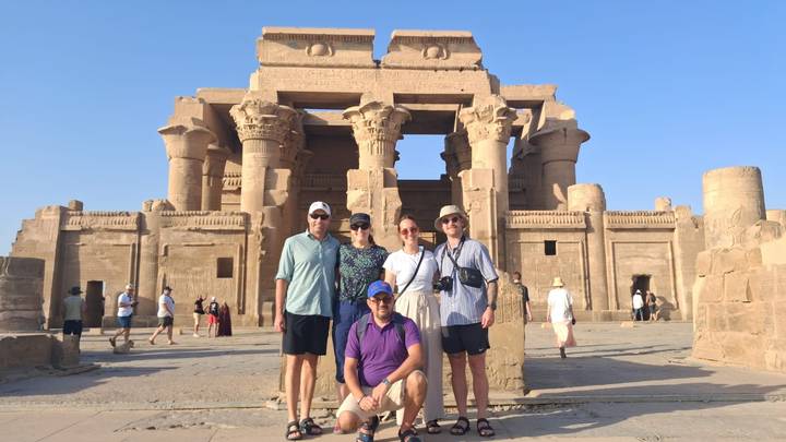 Group of tourists posing in front of Kom Ombo Temple on a bright afternoon