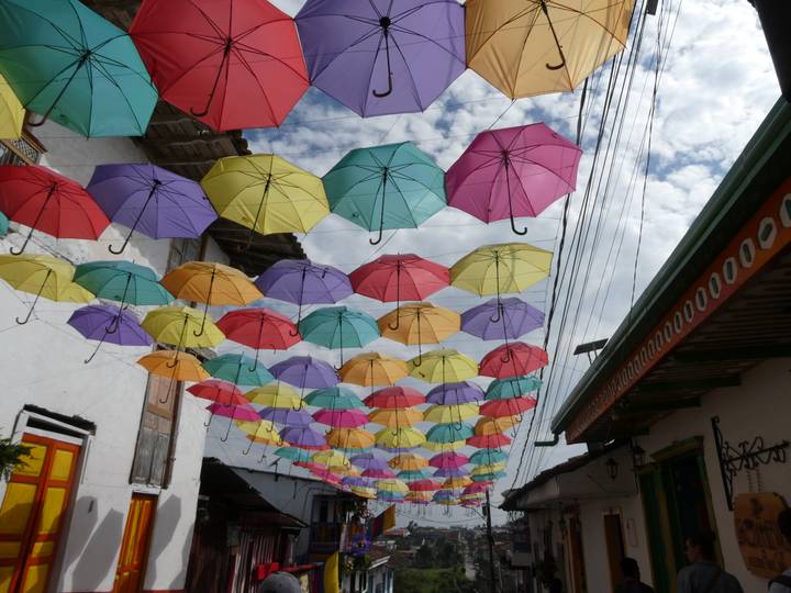 Colorful umbrellas suspended above a narrow colonial street lined with whitewashed buildings in Salento