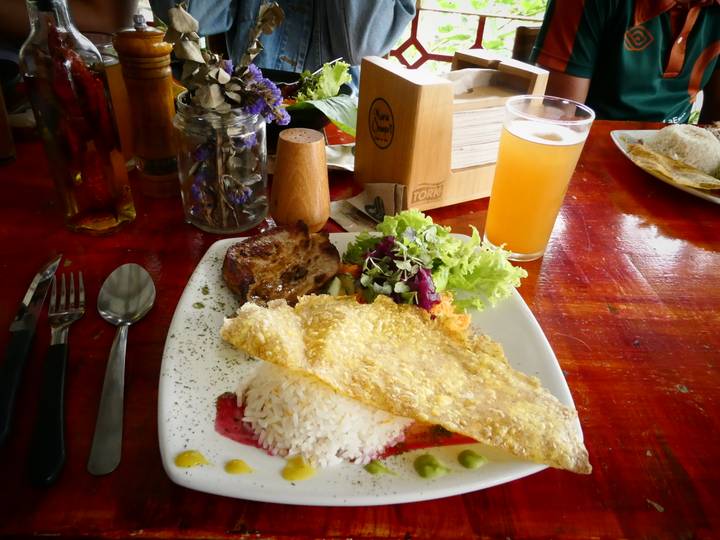 Colombian meal of grilled meat, rice, salad and beer served on a rustic wooden table