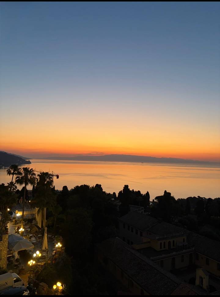 Brilliant orange sunset over the Mediterranean Sea with silhouetted palms and headland