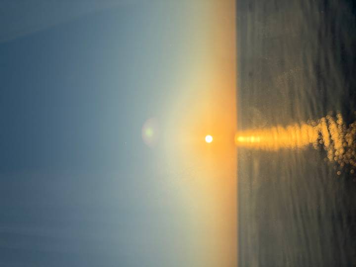 Setting sun casting a golden reflection across calm sea waters