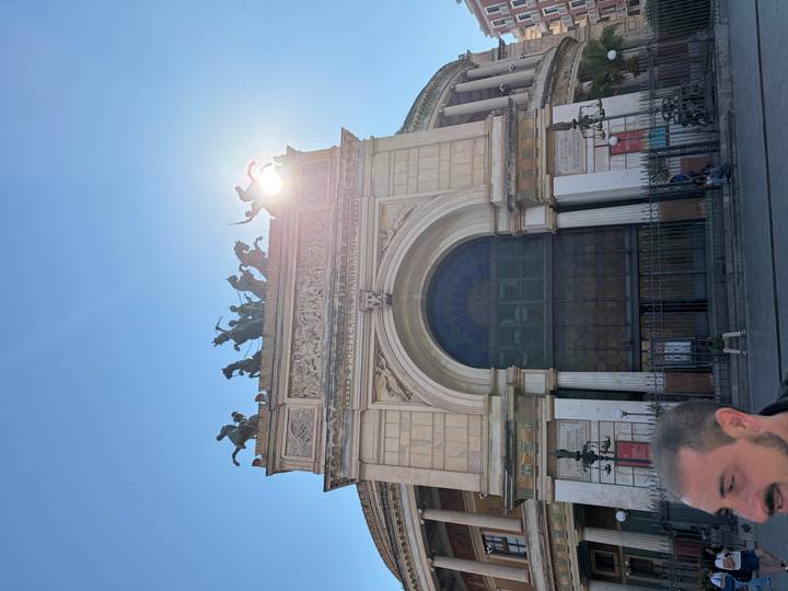 Front arch of Teatro Politeama Garibaldi with sun flare and bronze quadriga sculpture