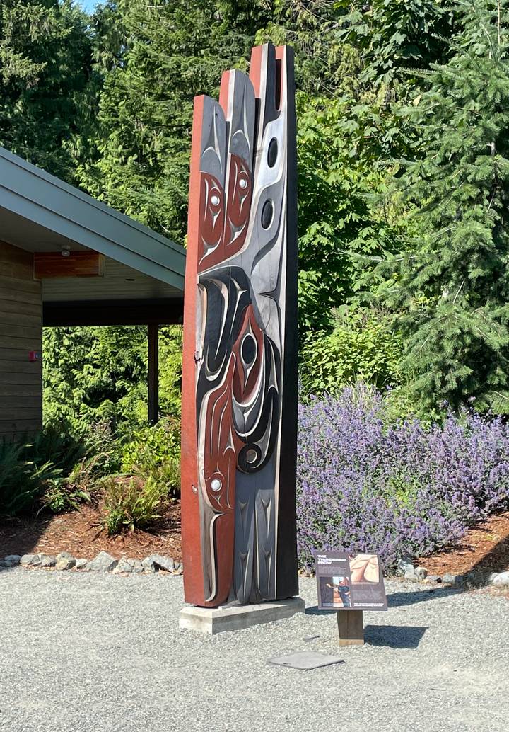Tall indigenous-style carved wooden pole set amid garden foliage