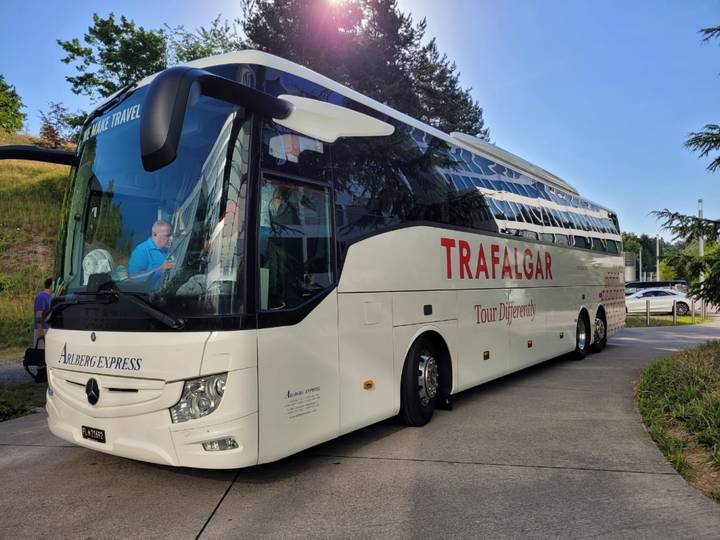 White Trafalgar tour coach parked on a roadside under bright daylight.