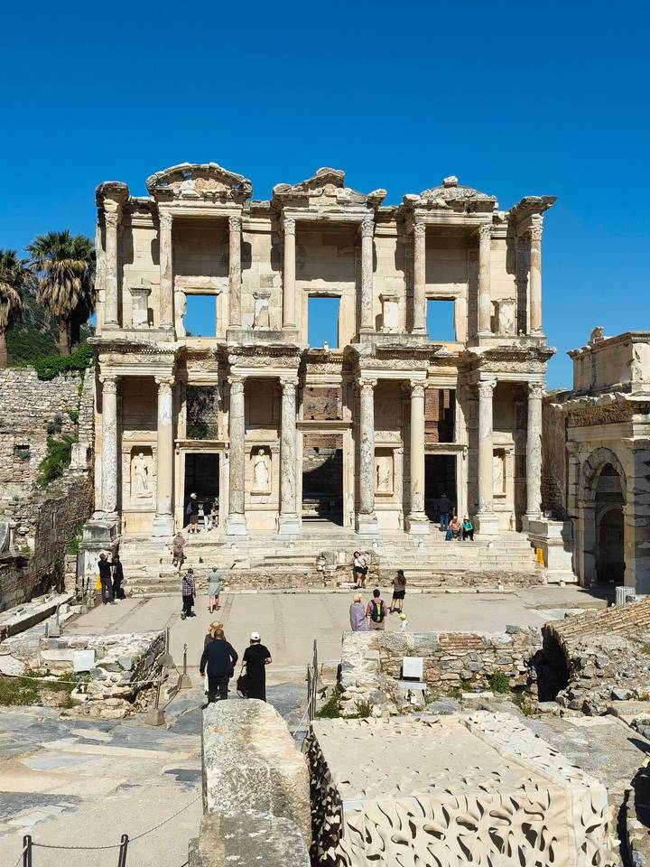 Grand marble façade of the Library of Celsus rises above visitors exploring the ancient ruins.